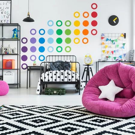 Buntes modernes Jugendzimmer mit Stickern an der Wand und einem Webteppich.